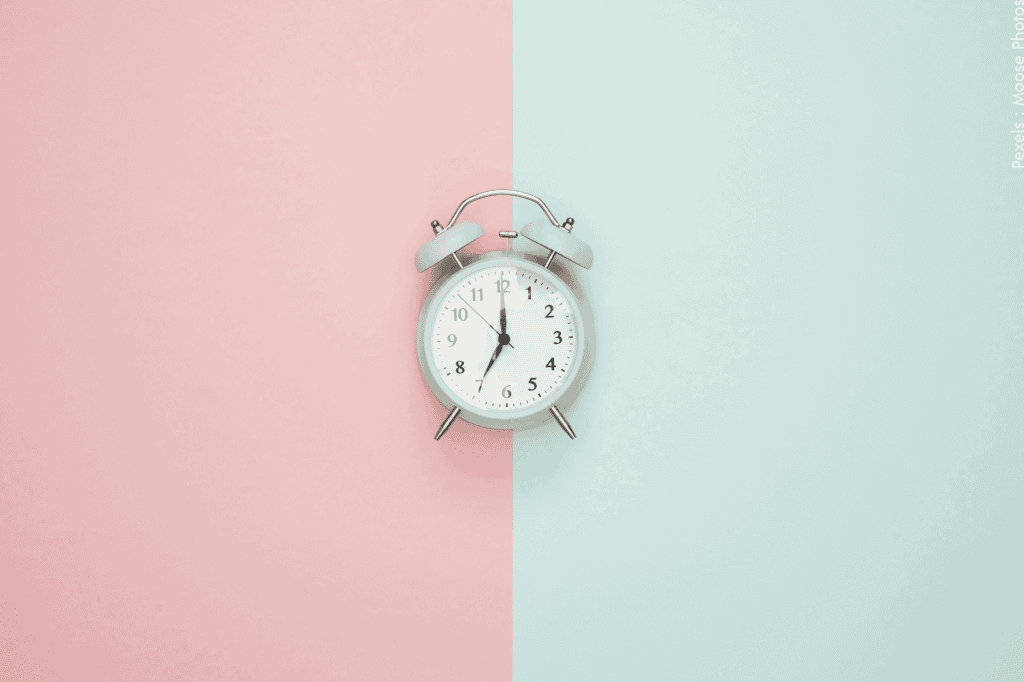 Une horloge ronde vintage sur un fond rose pastel et bleu.